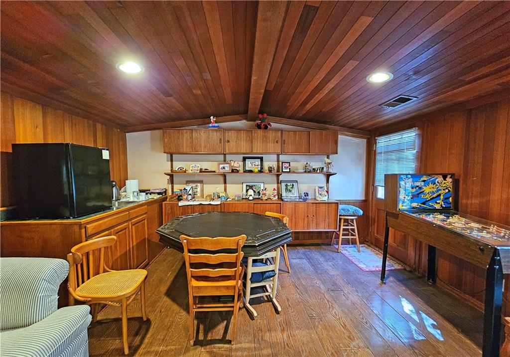 Kitchen featuring wood ceiling, dark hardwood / wood-style flooring, black refrigerator, and lofted ceiling with beams