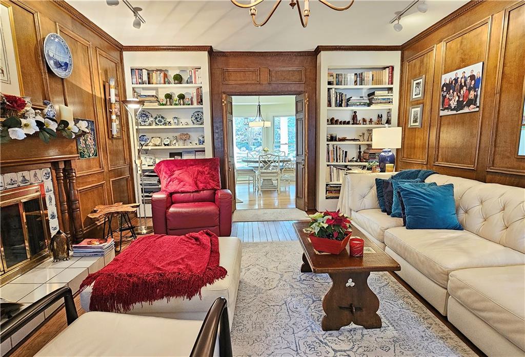 Living room featuring rail lighting, a notable chandelier, ornamental molding, and built in features