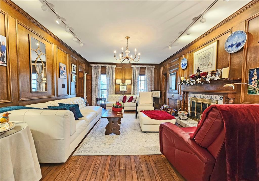 Living room featuring wood walls, crown molding, track lighting, an inviting chandelier, and dark hardwood / wood-style floors