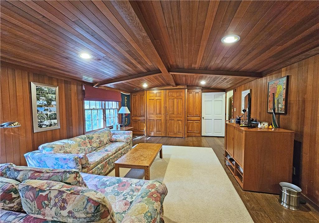 Living room featuring dark hardwood / wood-style flooring, wooden walls, wooden ceiling, and lofted ceiling with beams
