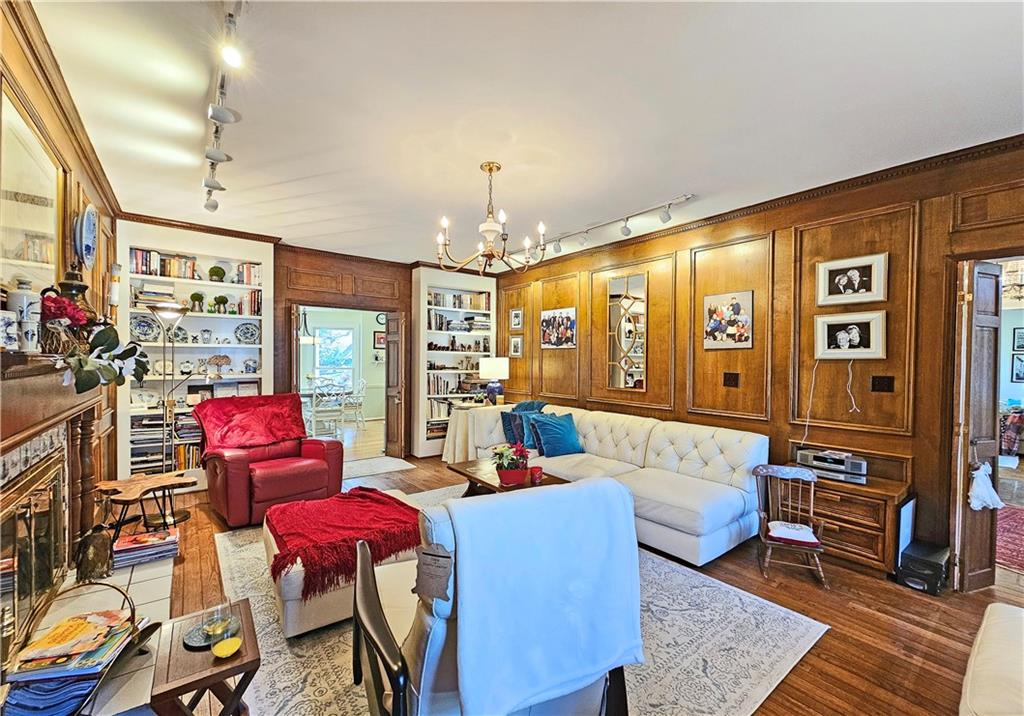 Living room featuring rail lighting, a chandelier, dark hardwood / wood-style floors, and built in features