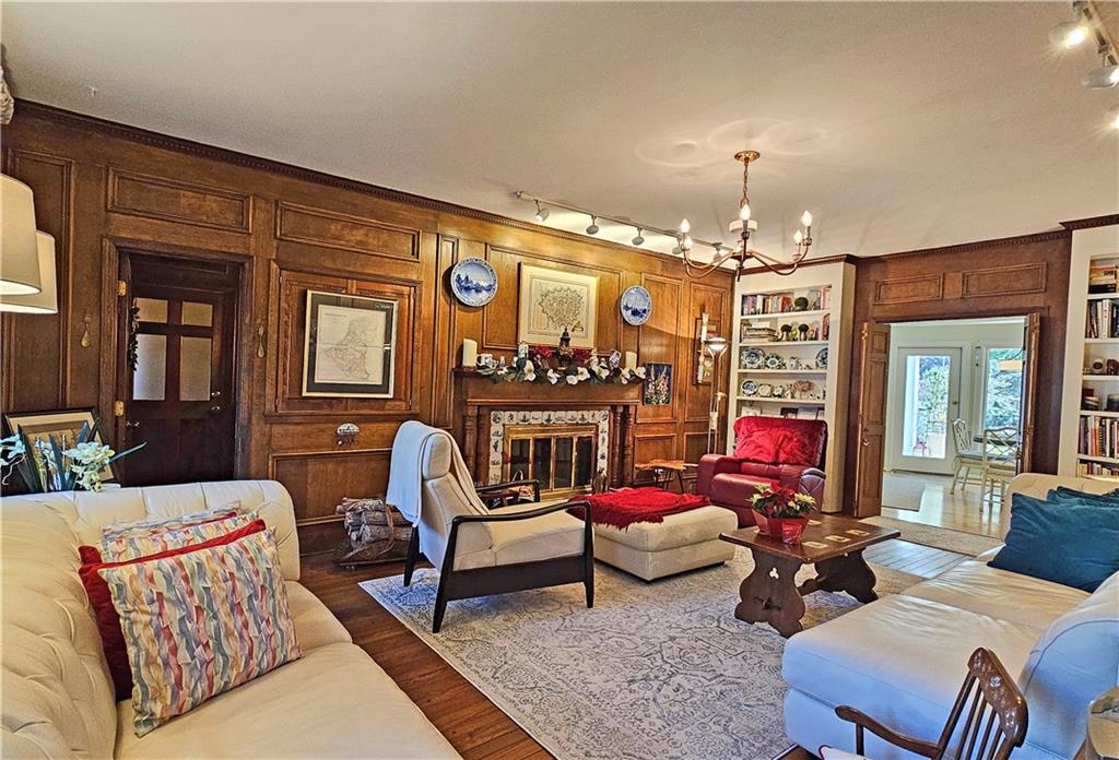 Living room featuring a notable chandelier, a fireplace, built in features, dark hardwood / wood-style floors, and wood walls