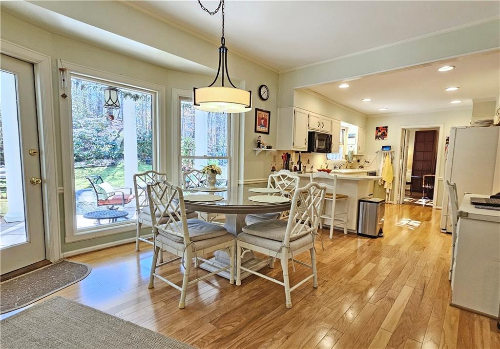Dining space with a wealth of natural light, light wood-type flooring, and ornamental molding
