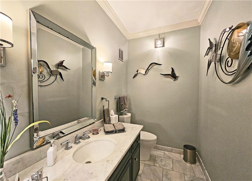 Bathroom with toilet, ornamental molding, tile floors, and vanity with extensive cabinet space