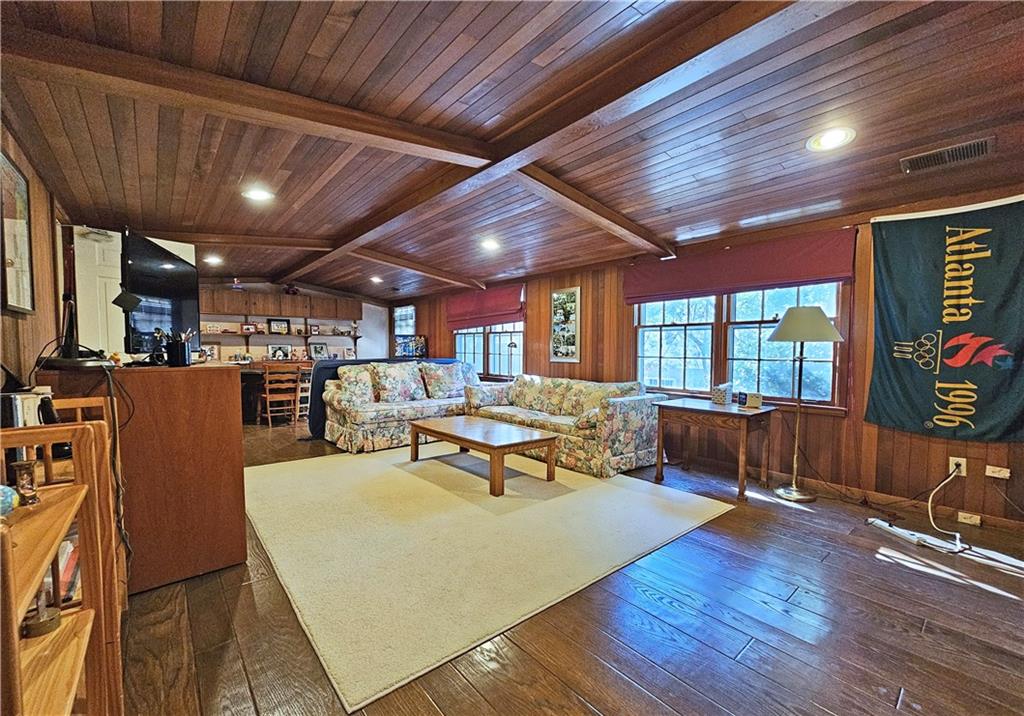 Living room with vaulted ceiling with beams, wood walls, dark hardwood / wood-style flooring, and wooden ceiling