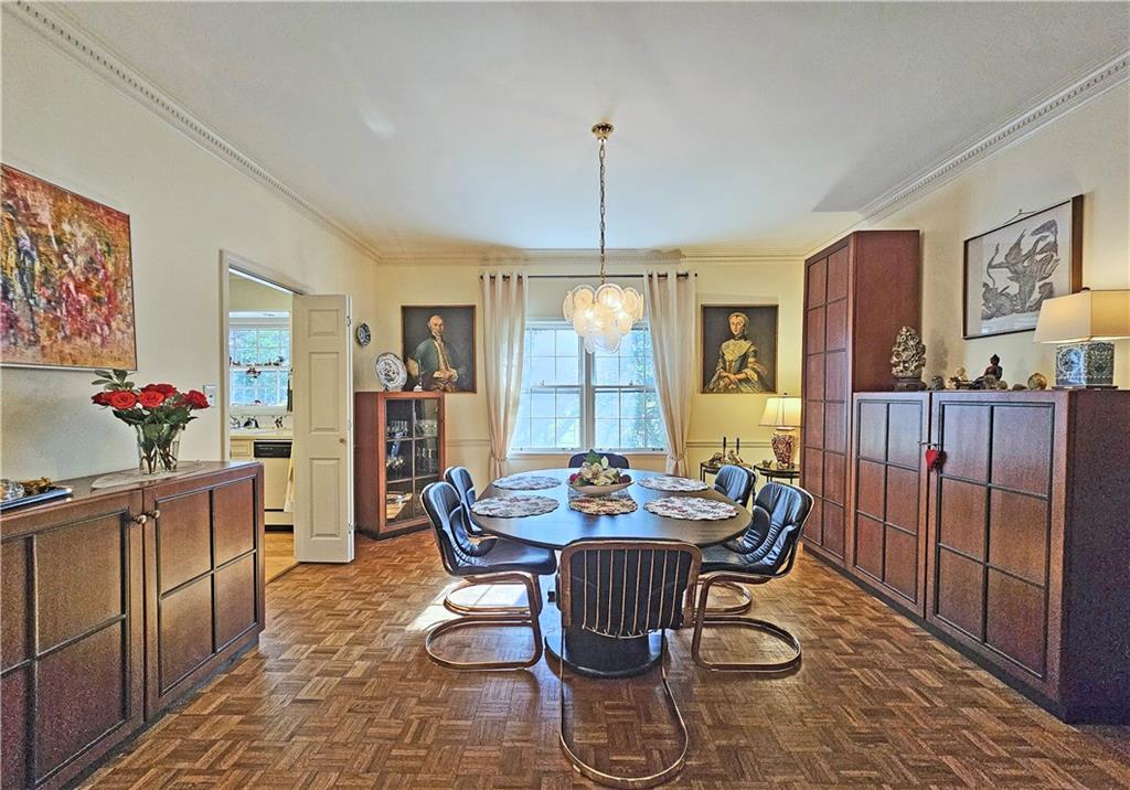 Dining space with an inviting chandelier, crown molding, and dark parquet flooring