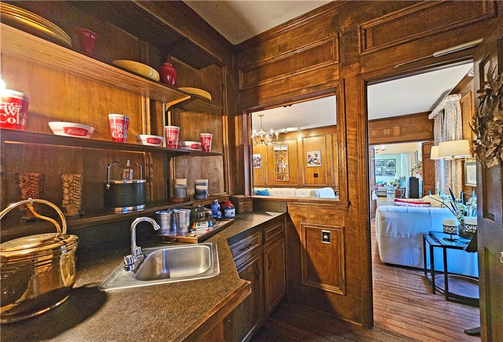 Kitchen featuring a chandelier, dark wood-type flooring, wood walls, and sink