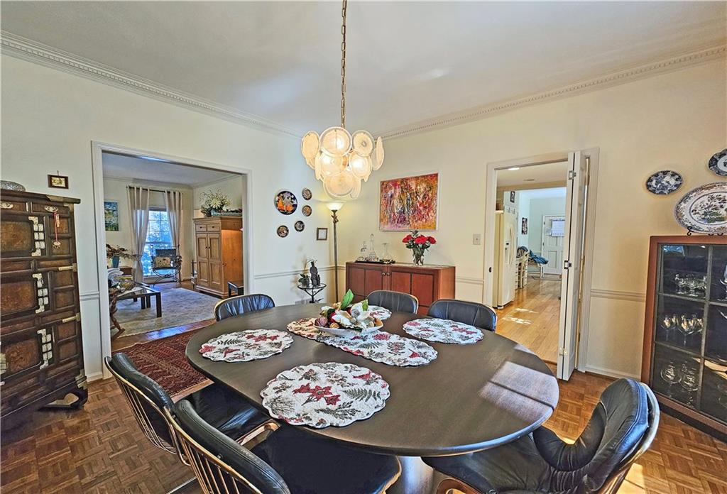 Dining room featuring dark parquet floors, an inviting chandelier, and ornamental molding