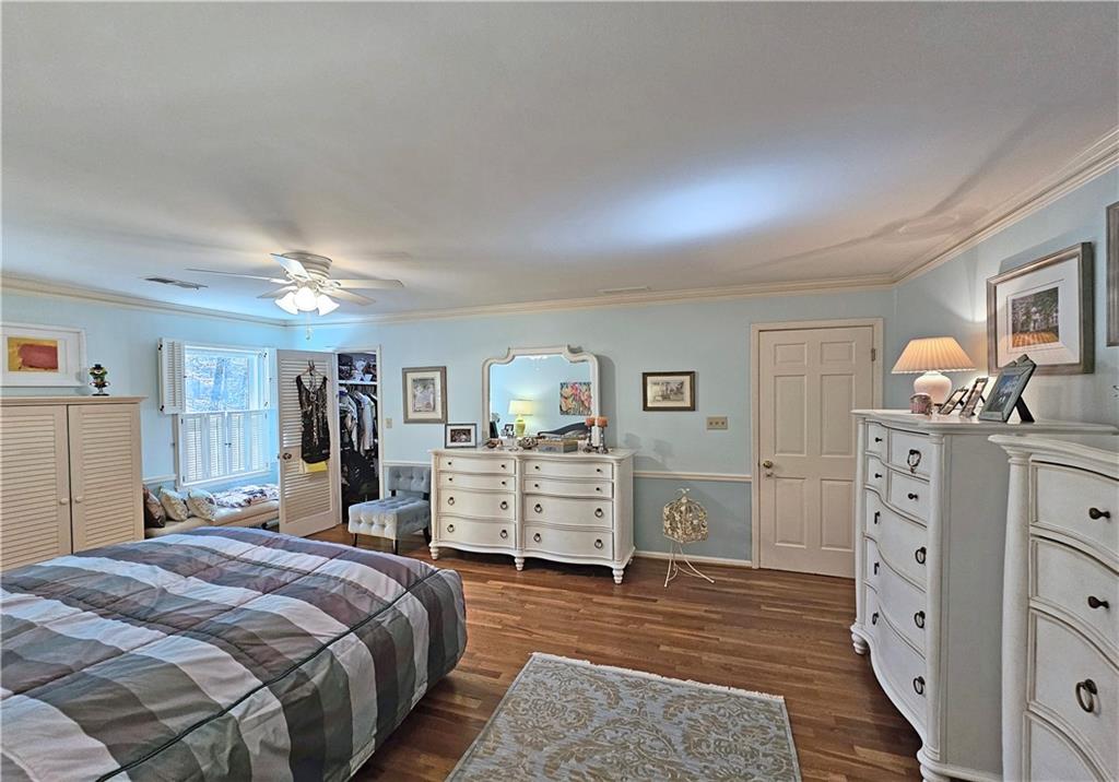 Bedroom featuring dark wood-type flooring, ceiling fan, ornamental molding, a closet, and a walk in closet