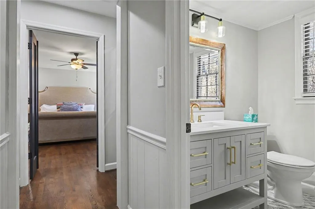 Ensuite bathroom featuring vanity, ornamental molding, dark wood-style flooring, and a ceiling fan