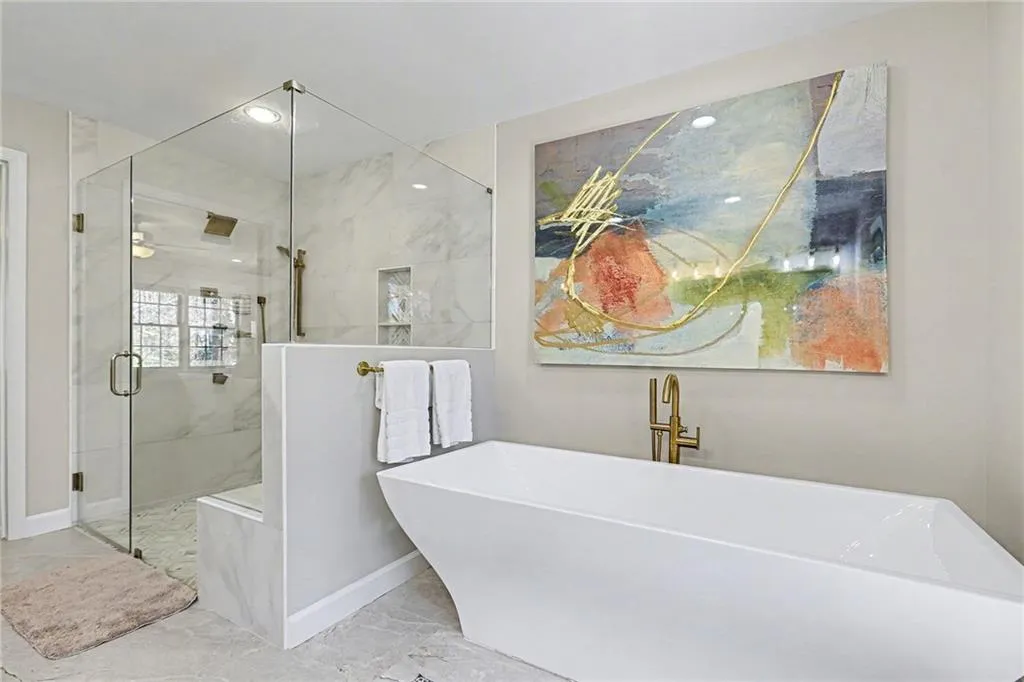 Bathroom with a freestanding tub, a marble finish shower, light marble finish floors, and recessed lighting