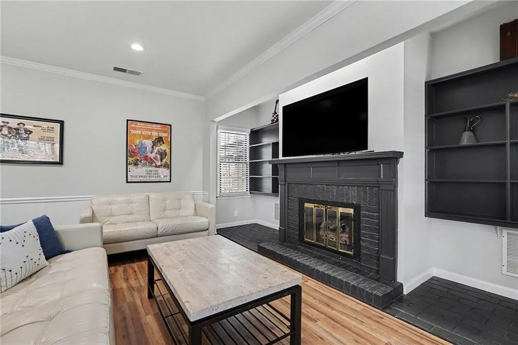 Living room featuring built in features, ornamental molding, light wood finished floors, a fireplace, and recessed lighting
