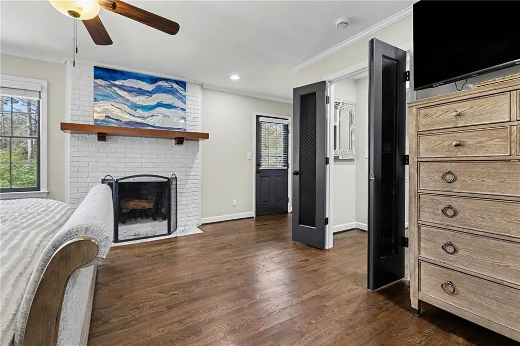 Unfurnished bedroom with crown molding, a ceiling fan, dark wood-style floors, a fireplace, and recessed lighting