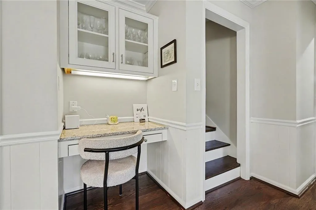 Home office featuring dark wood-style floors, a wainscoted wall, and built in desk