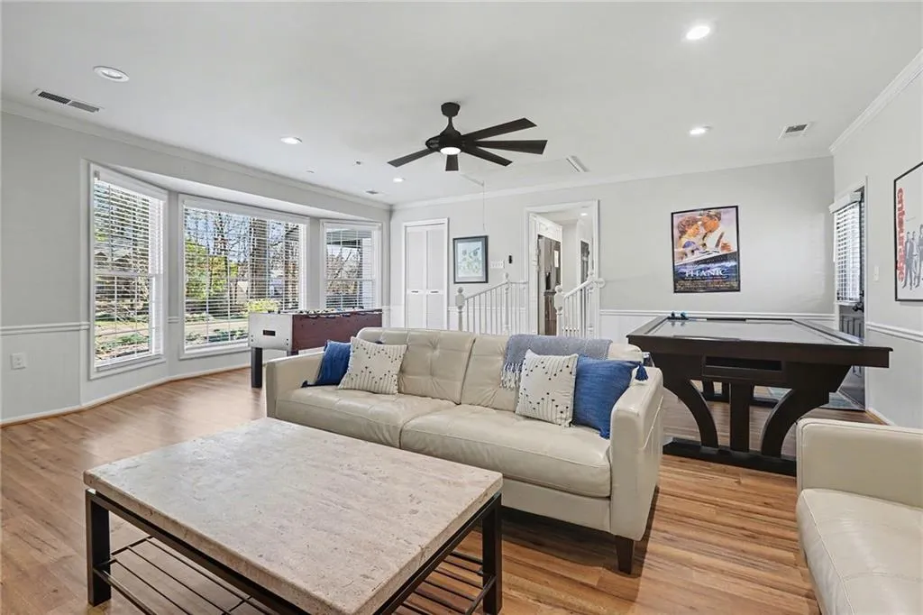 Living area featuring a wainscoted wall, ceiling fan, ornamental molding, recessed lighting, and light wood-style floors