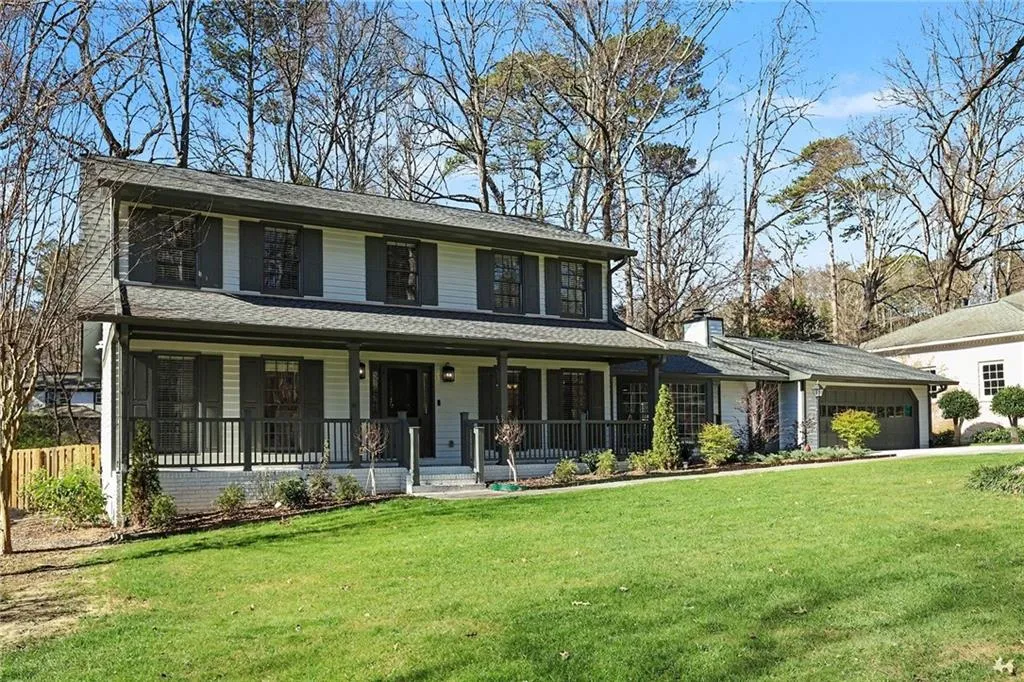 View of front facade featuring covered porch, a front lawn, a shingled roof, and an attached garage