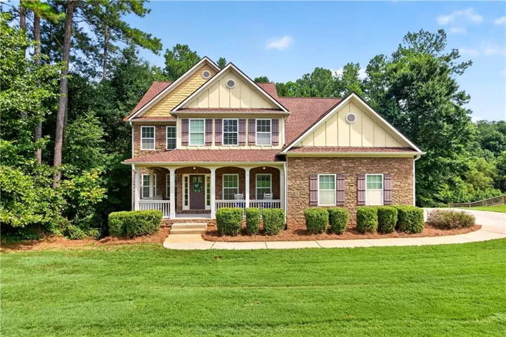 Two-story residence featuring a brick and siding exterior with a covered front porch, an arched entryway, and mature landscaping