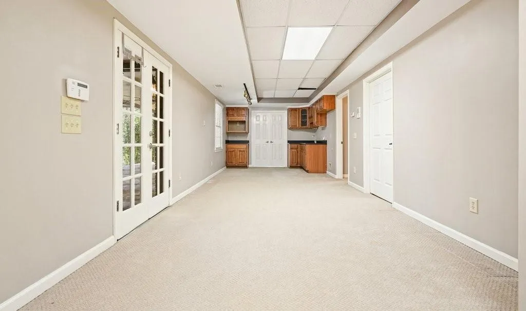 Unfurnished room with a drop ceiling, baseboards, and light colored carpet
