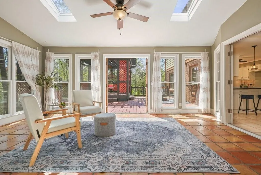 Sunroom / solarium featuring tile patterned flooring and vaulted ceiling with skylight