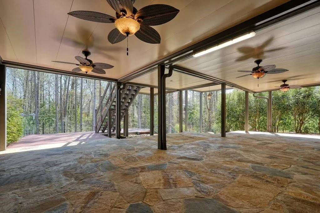 View of patio with stairs, ceiling fan, and a wooded view