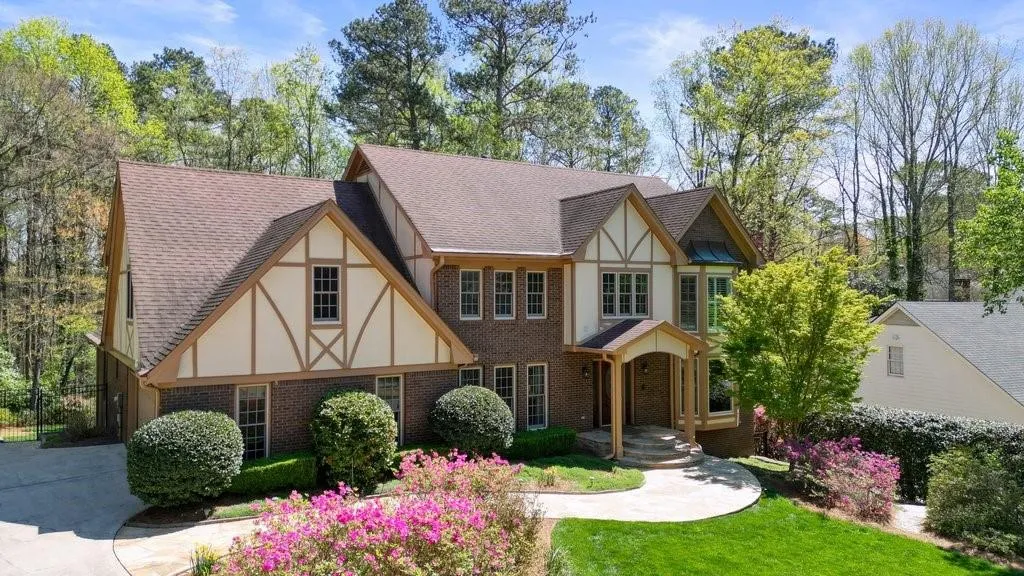 Tudor house featuring brick siding, a front yard, stucco siding, and a shingled roof