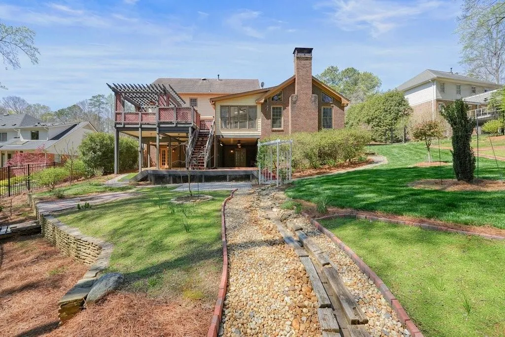 Rear view of property featuring fence, a wooden deck, stairs, a yard, and a pergola