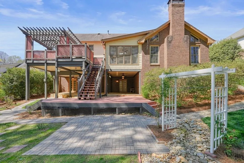 Back of house with stairs, a pergola, a deck, and a chimney
