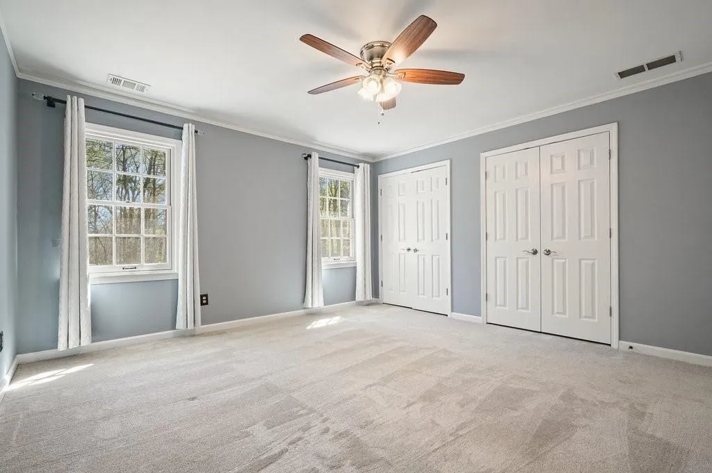 Unfurnished bedroom featuring crown molding, multiple closets, and visible vents