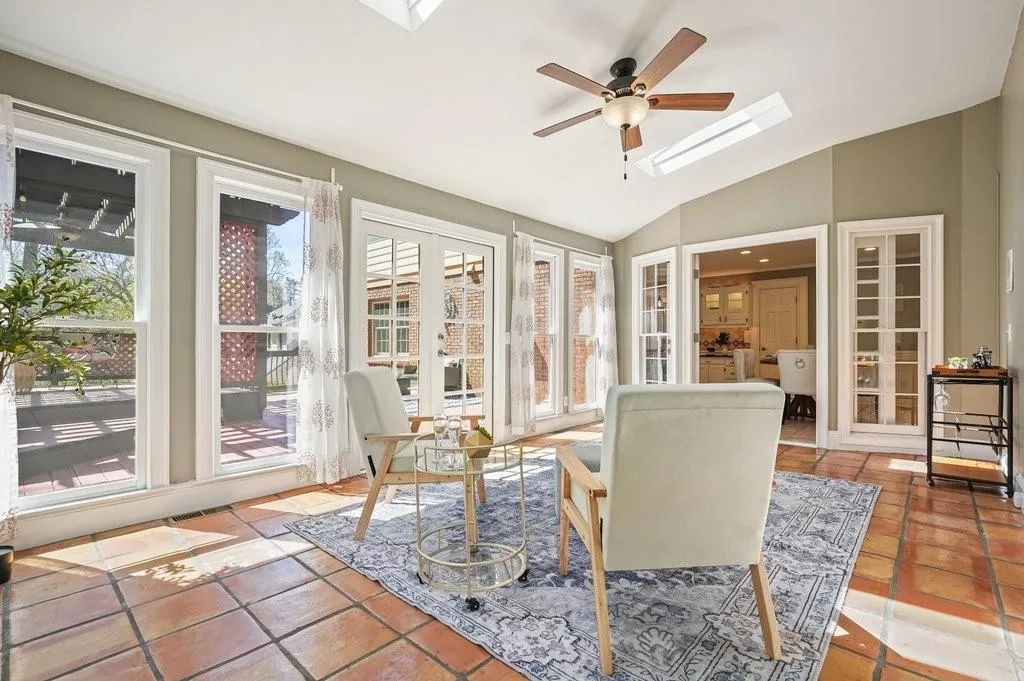 Sunroom featuring french doors, lofted ceiling with skylight, tile patterned flooring, and visible vents