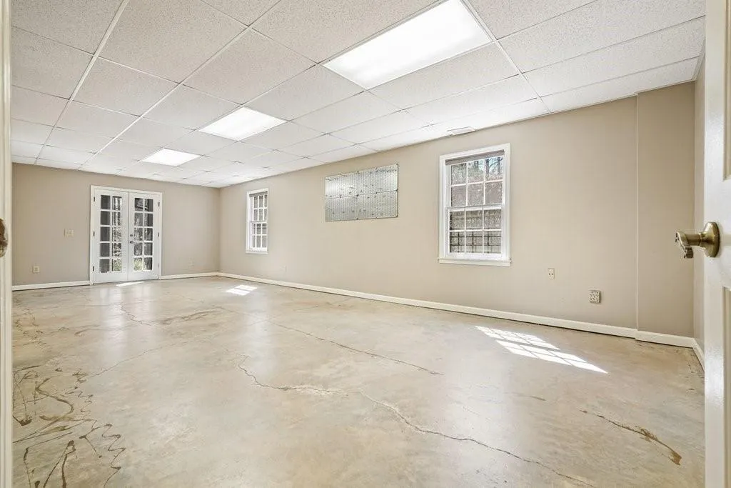 Spare room featuring french doors, concrete floors, baseboards, and a paneled ceiling