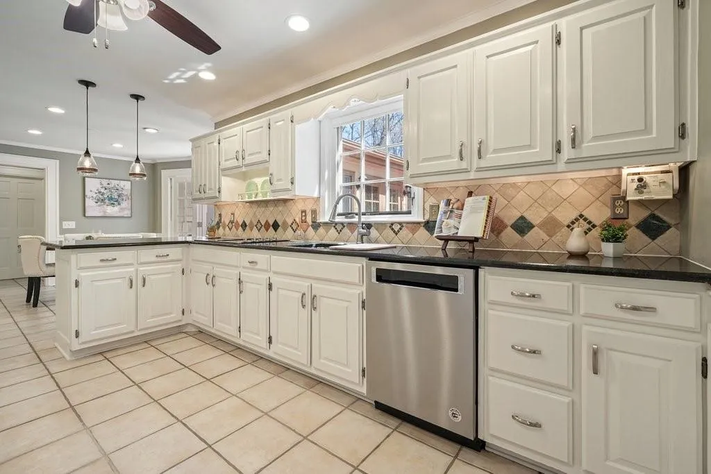 Kitchen featuring a sink, dark countertops, a peninsula, and dishwasher