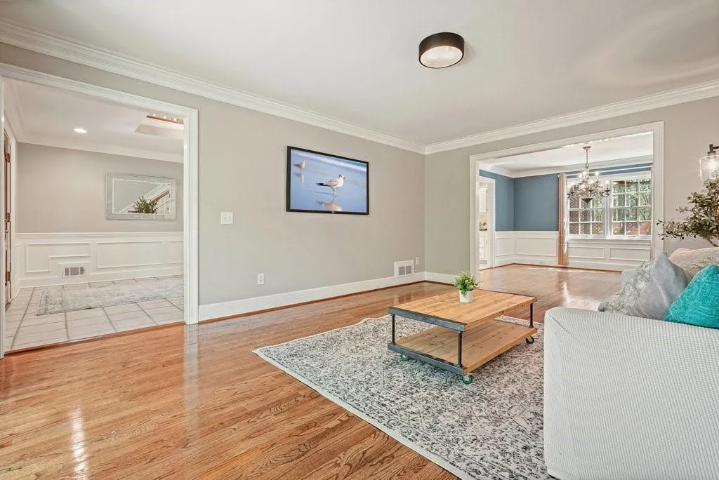 Living room featuring crown molding, visible vents, a notable chandelier, and wood finished floors