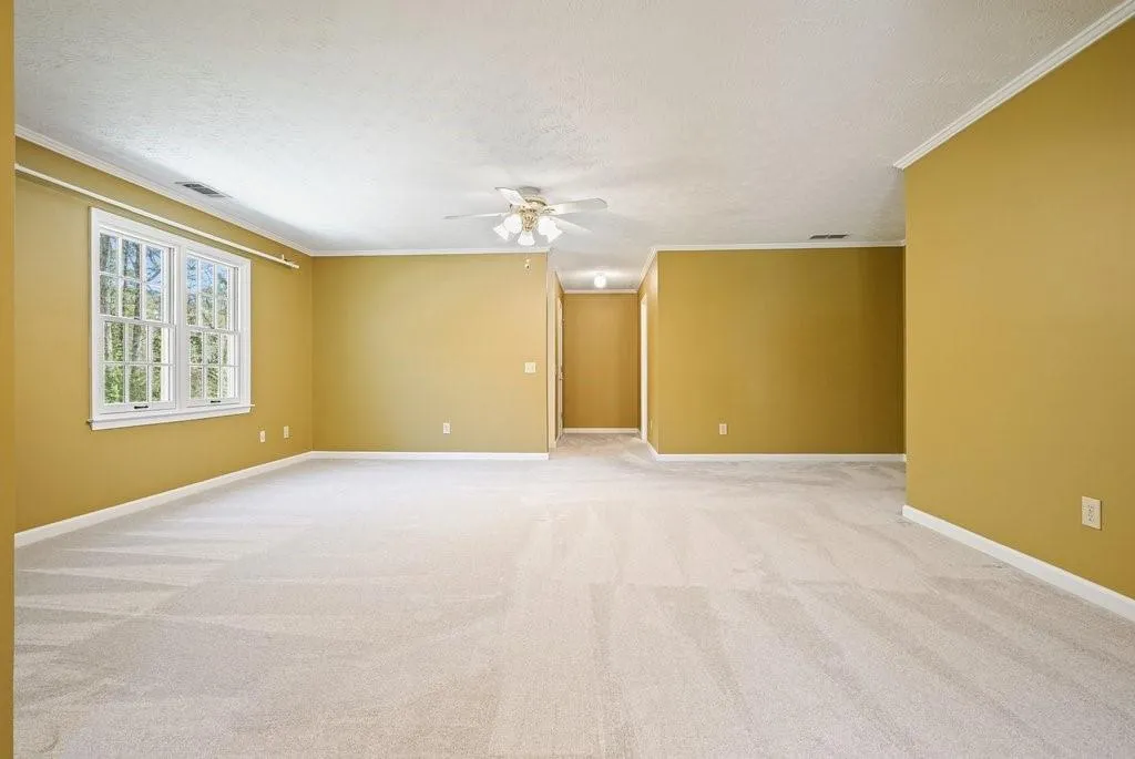 Unfurnished room with a textured ceiling, visible vents, baseboards, ceiling fan, and ornamental molding