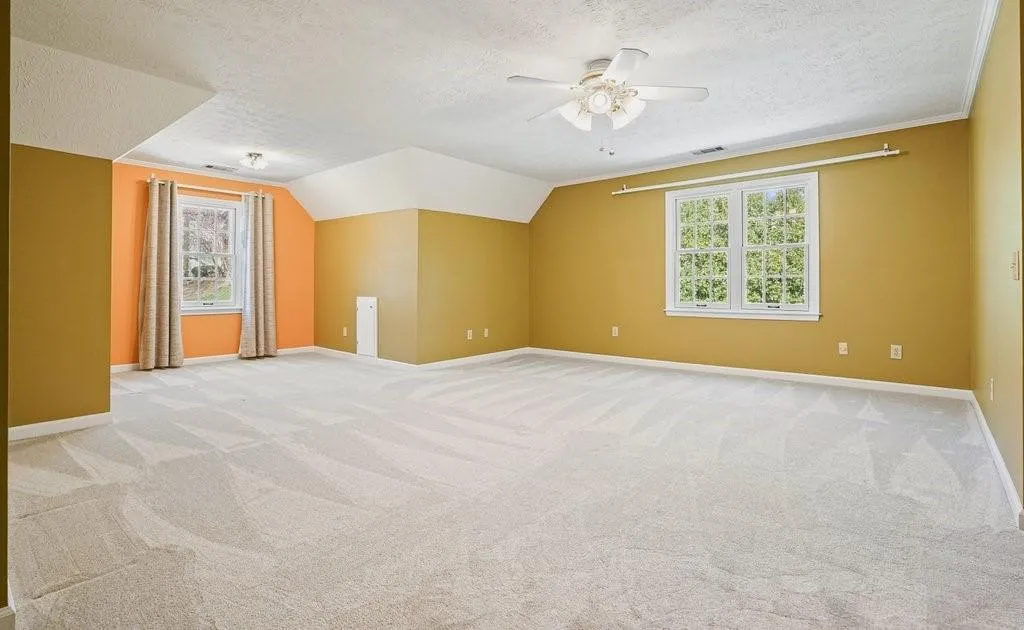 Additional living space with vaulted ceiling, a textured ceiling, baseboards, light colored carpet, and ceiling fan