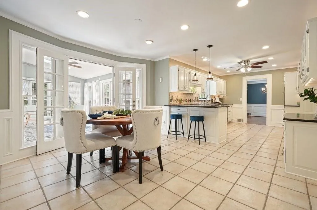 Dining area featuring a decorative wall, a ceiling fan, and light tile patterned floors