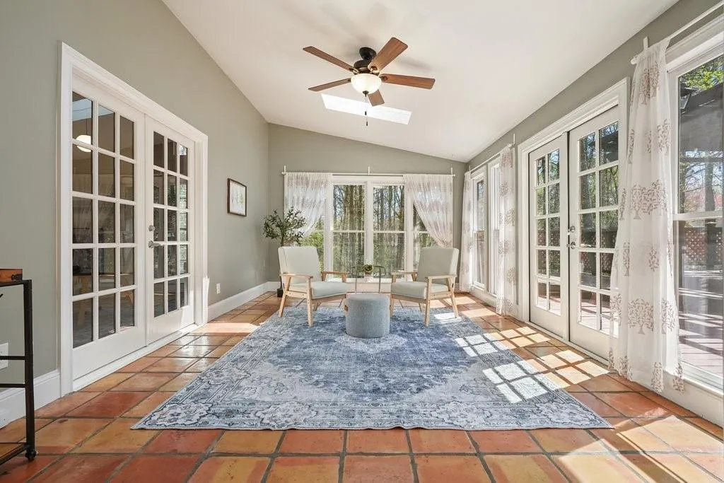 Sunroom / solarium featuring vaulted ceiling with skylight, french doors, and tile patterned flooring