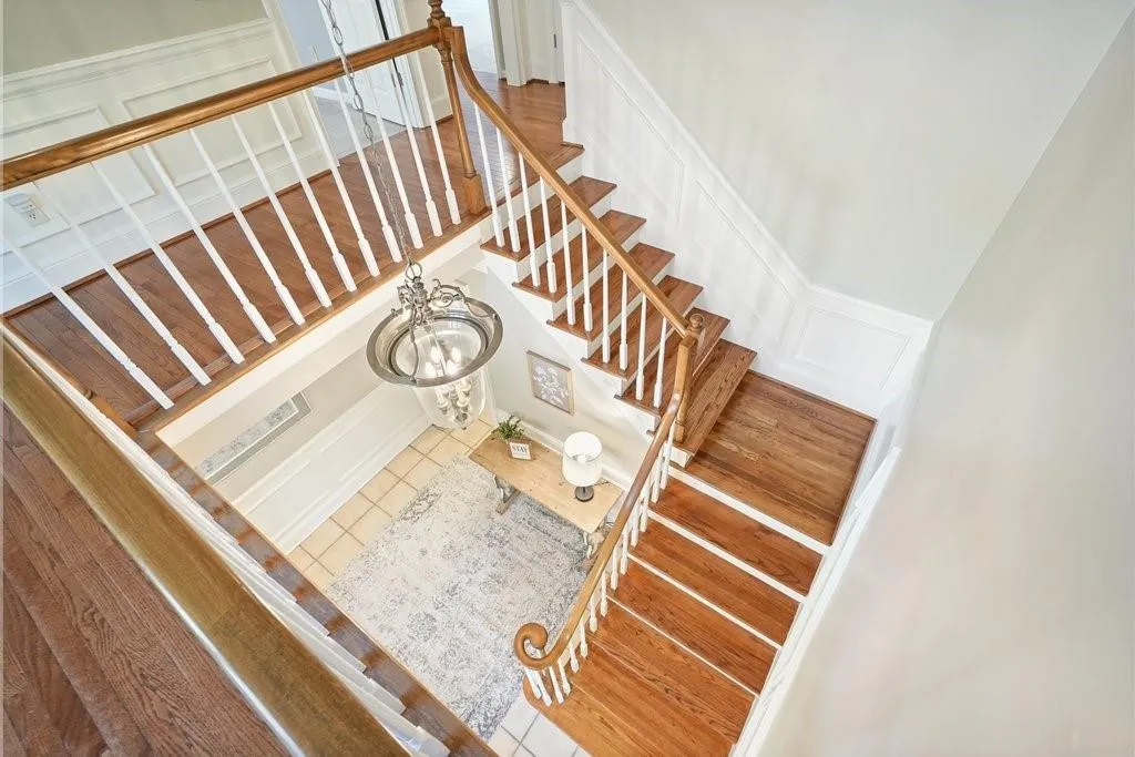 Staircase with a decorative wall, a wainscoted wall, a notable chandelier, and tile patterned floors