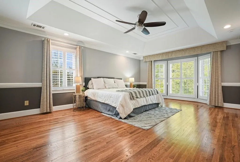 Bedroom featuring hardwood / wood-style floors, multiple windows, crown molding, and a raised ceiling