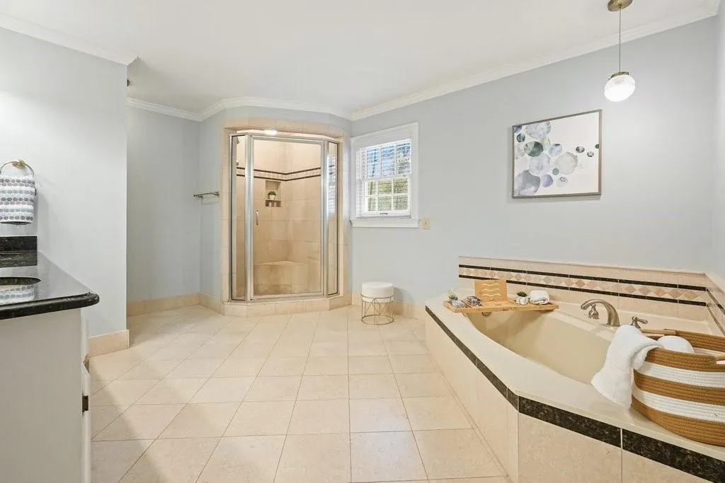 Bathroom with tile patterned flooring, vanity, crown molding, a stall shower, and a garden tub