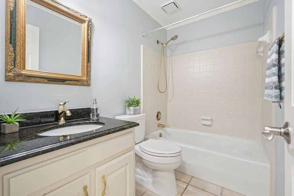 Bathroom featuring tile patterned flooring, vanity, crown molding, toilet, and  shower combination