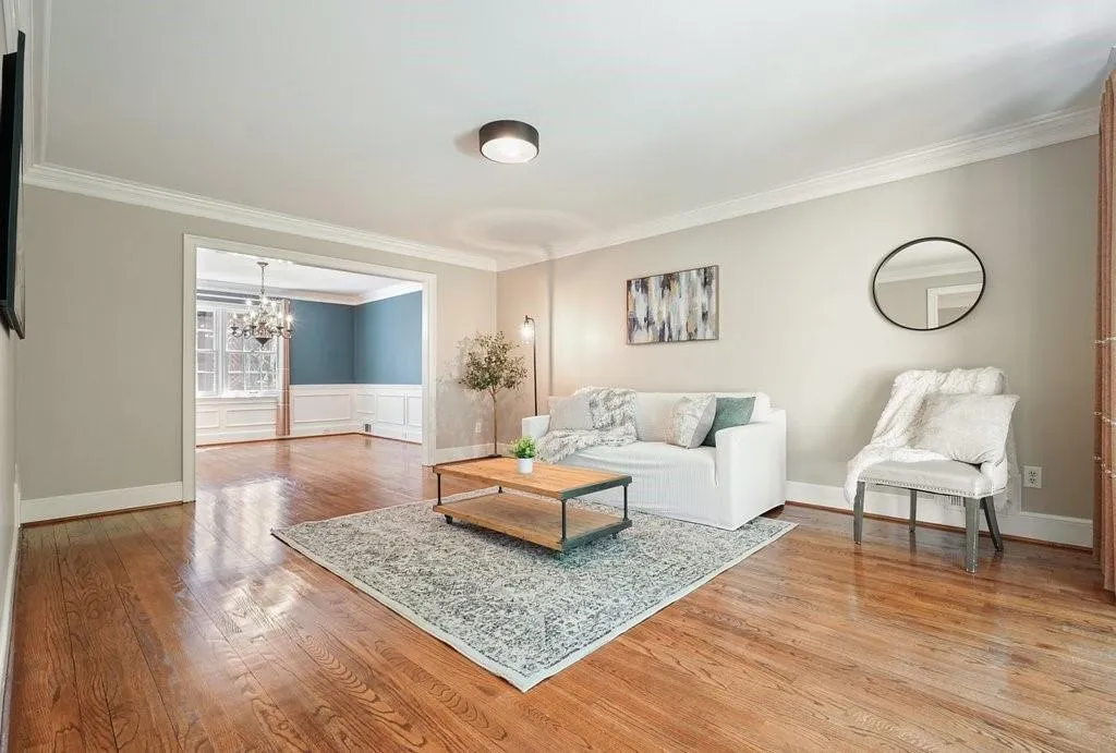Living room featuring ornamental molding, baseboards, a chandelier, a wainscoted wall, and wood finished floors