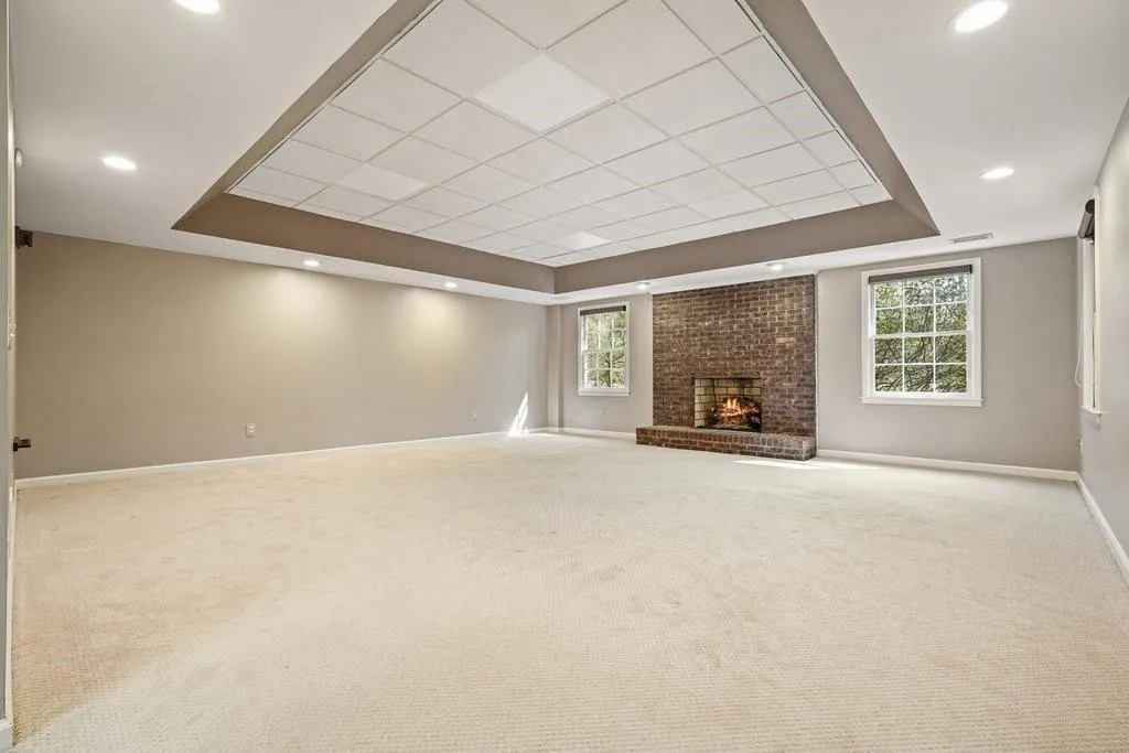 Unfurnished living room featuring a tray ceiling, baseboards, and carpet