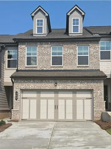 Brick facade townhome with a two-car garage featuring decorative hardware