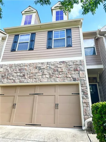Exterior featuring stone facade, tan horizontal siding, and two dormer windows