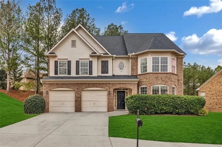 Two-story residence featuring brick and stucco siding, a two-car garage, and a prominent bay window