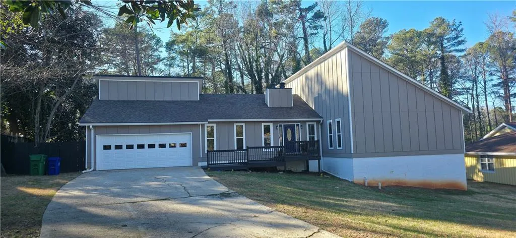 Contemporary exterior with a multi-level roofline, attached garage, front deck, and a paved driveway