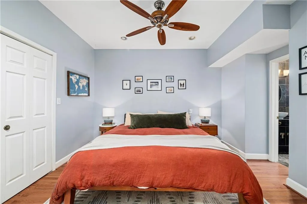 Bedroom featuring wood finished floors, a ceiling fan, and connected bathroom