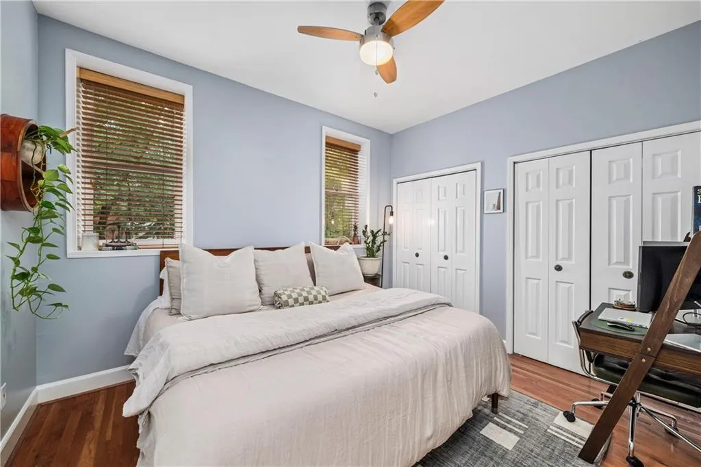 Bedroom with wood finished floors, two closets, a ceiling fan, and a desk