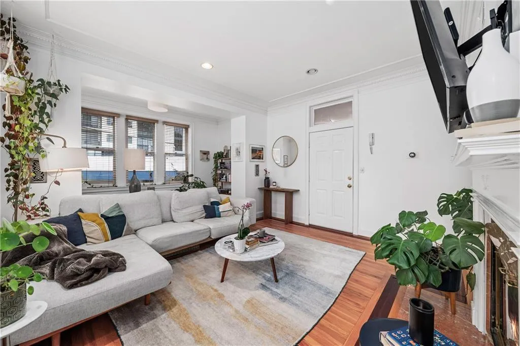 Living area featuring a fireplace with flush hearth, crown molding, wood finished floors, and recessed lighting
