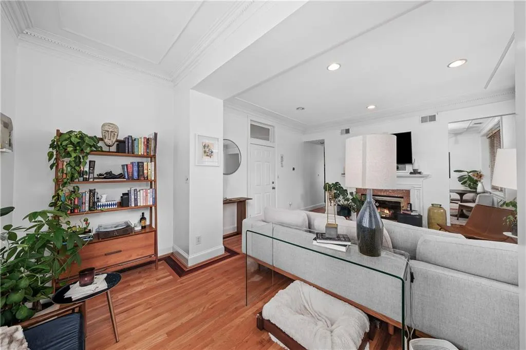 Living area with ornamental molding, light wood finished floors, a glass covered fireplace, and recessed lighting